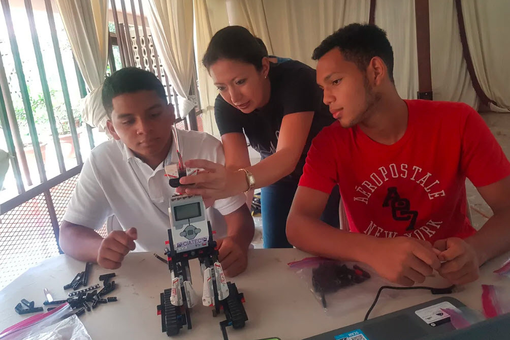 Victoria Serrano (middle) helps two students install an infrared sensor on their Lego Mindstorms robot. Photo: Angelica Calderon