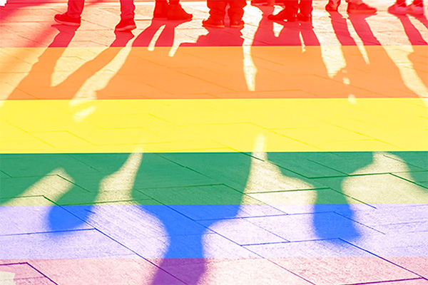 Shadows of people standing in line overlaid with a rainbow.