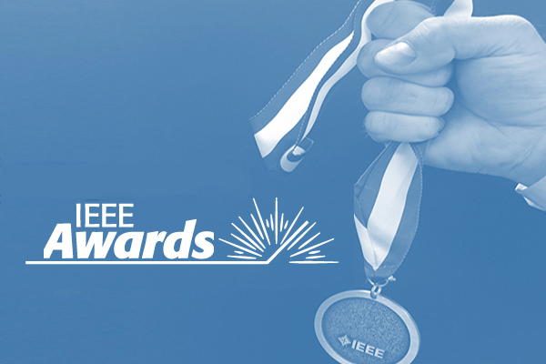 A hand holding an IEEE Medal on a blue background, with IEEE Awards logo in white.