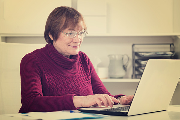 A smiling woman types on a laptop.